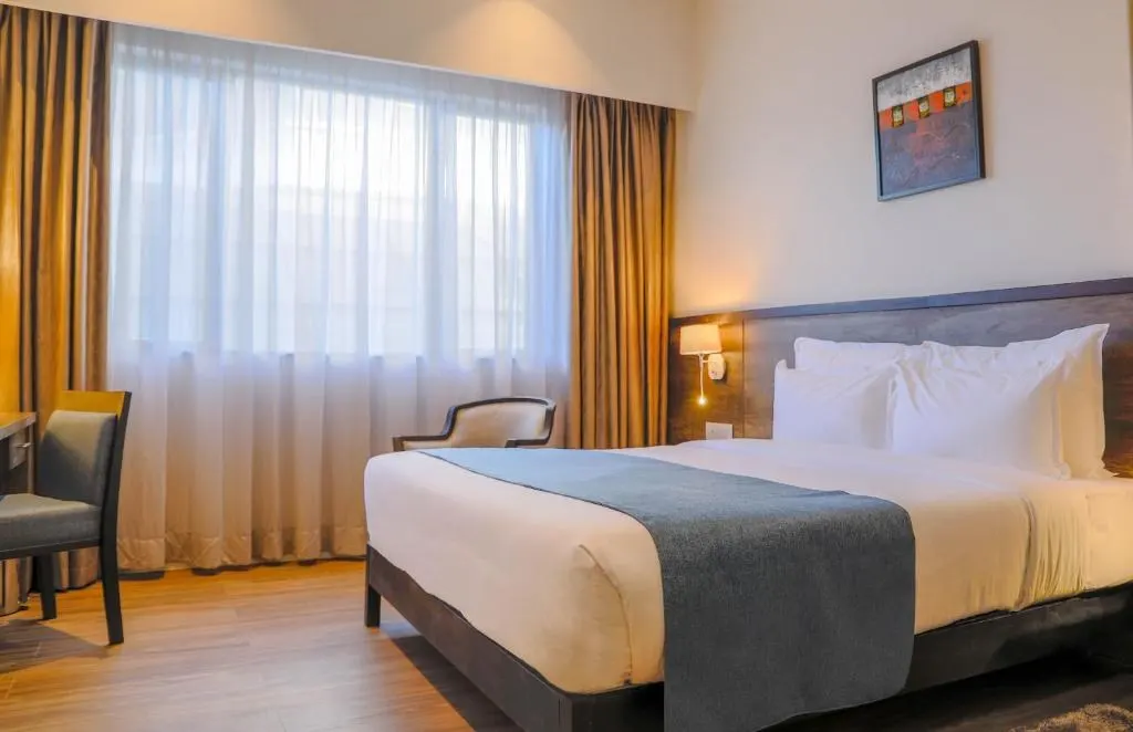 Guest room with a large bed, desk and curtained windows at Eka Hotel Eldoret